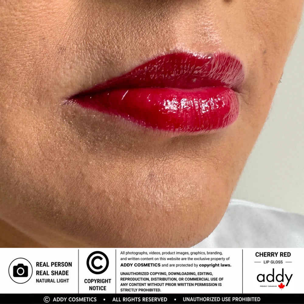 Close-up of a person's lips wearing a glossy cherry red lip gloss, with a white banner at the bottom containing product information and the ADDY COSMETICS brand name.