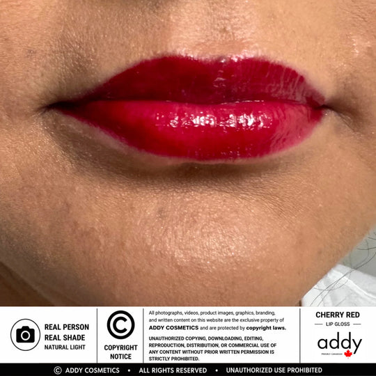 Close-up of glossy bright red lipstick applied to lips, with the brand name &