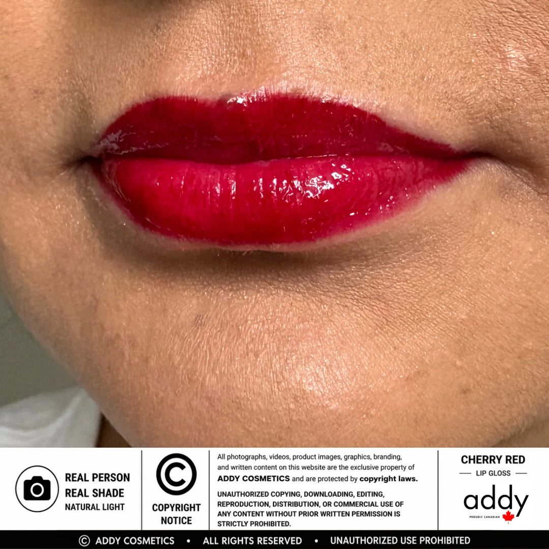 Close-up of glossy cherry red lip gloss applied to lips, with a white information banner at the bottom reading &