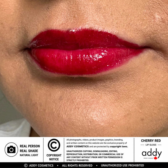 Close-up of glossy cherry red lip gloss applied to lips, with a white information banner at the bottom reading &