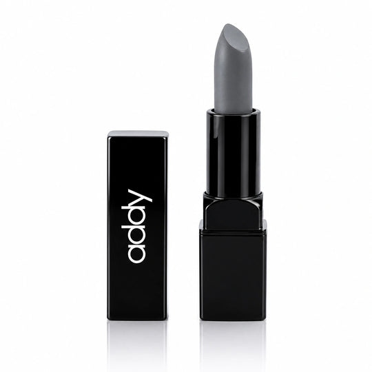 A matte gray lipstick in a glossy black rectangular tube, shown next to its matching black cap on a clean white background.